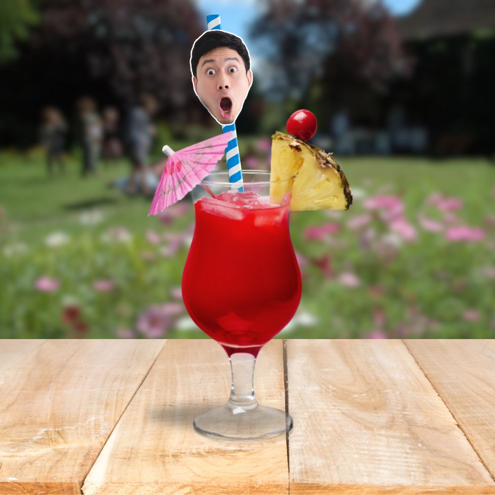 Red drink with a personalised face straw, set on a table with a blurred outdoor party background